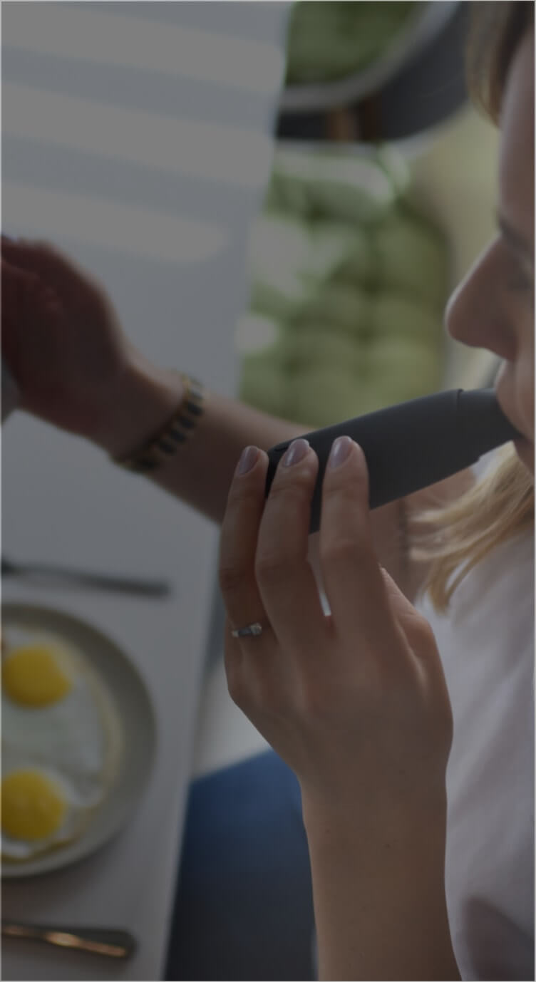 A woman blows on Lumen's device