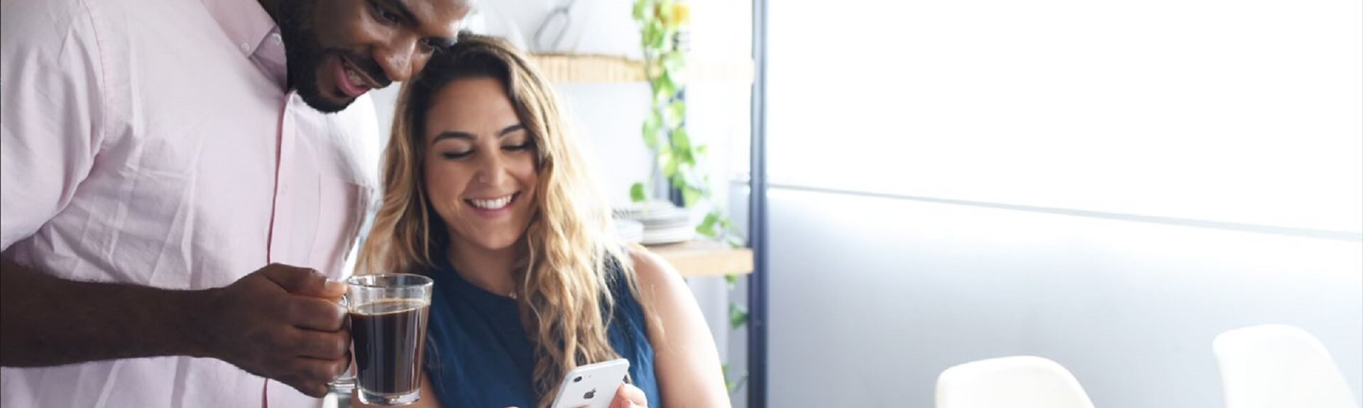 A man holds a cup of coffee and a woman are looking at Lumen's application