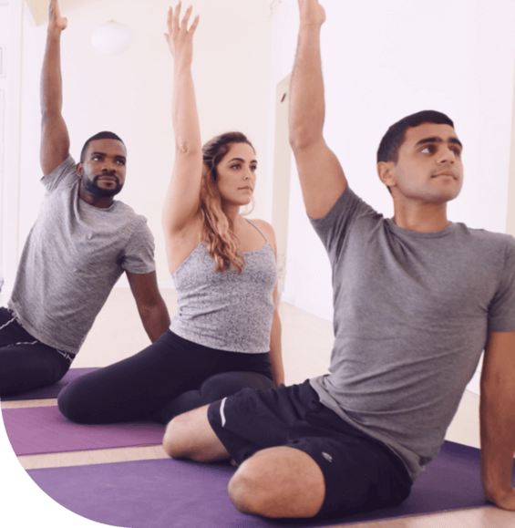 3 people sit on 3 purple sports mattresses and raise one hand